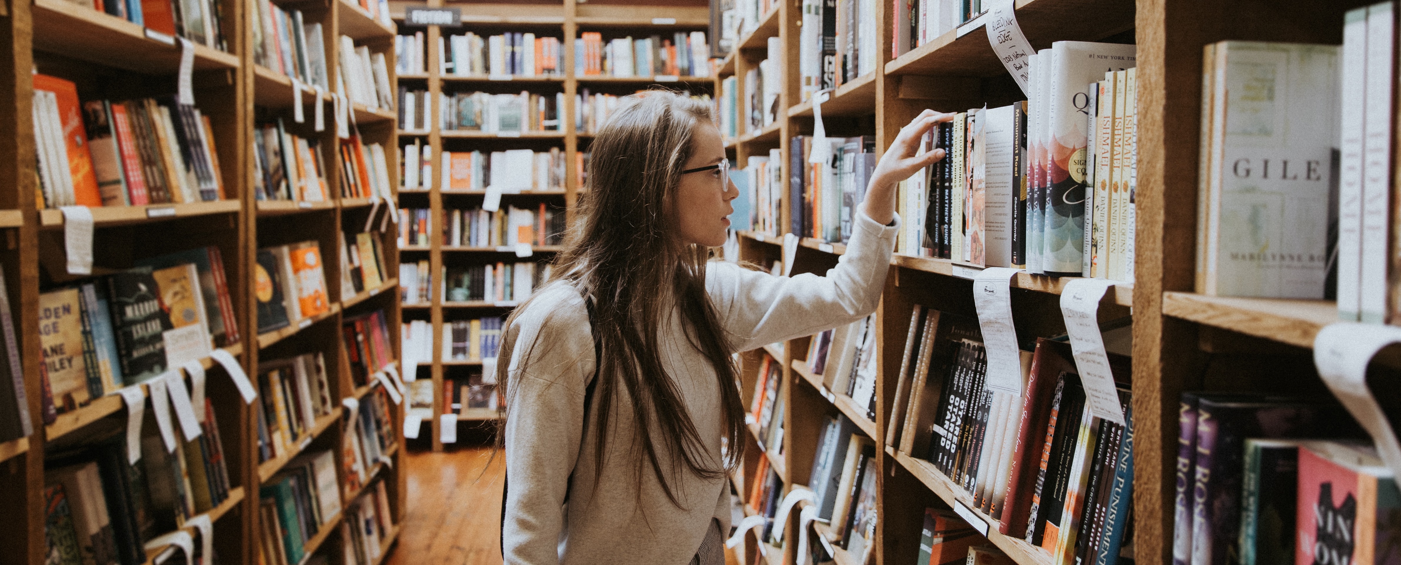 An alumnus looks through books on library shelves 