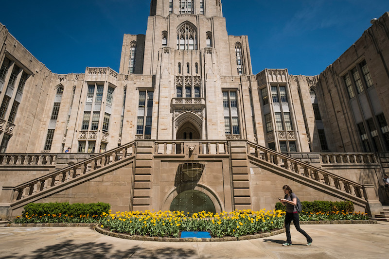 A student walks past the Cathedral of Learning fountain