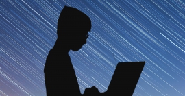 Silhouette of a person holding a laptop 